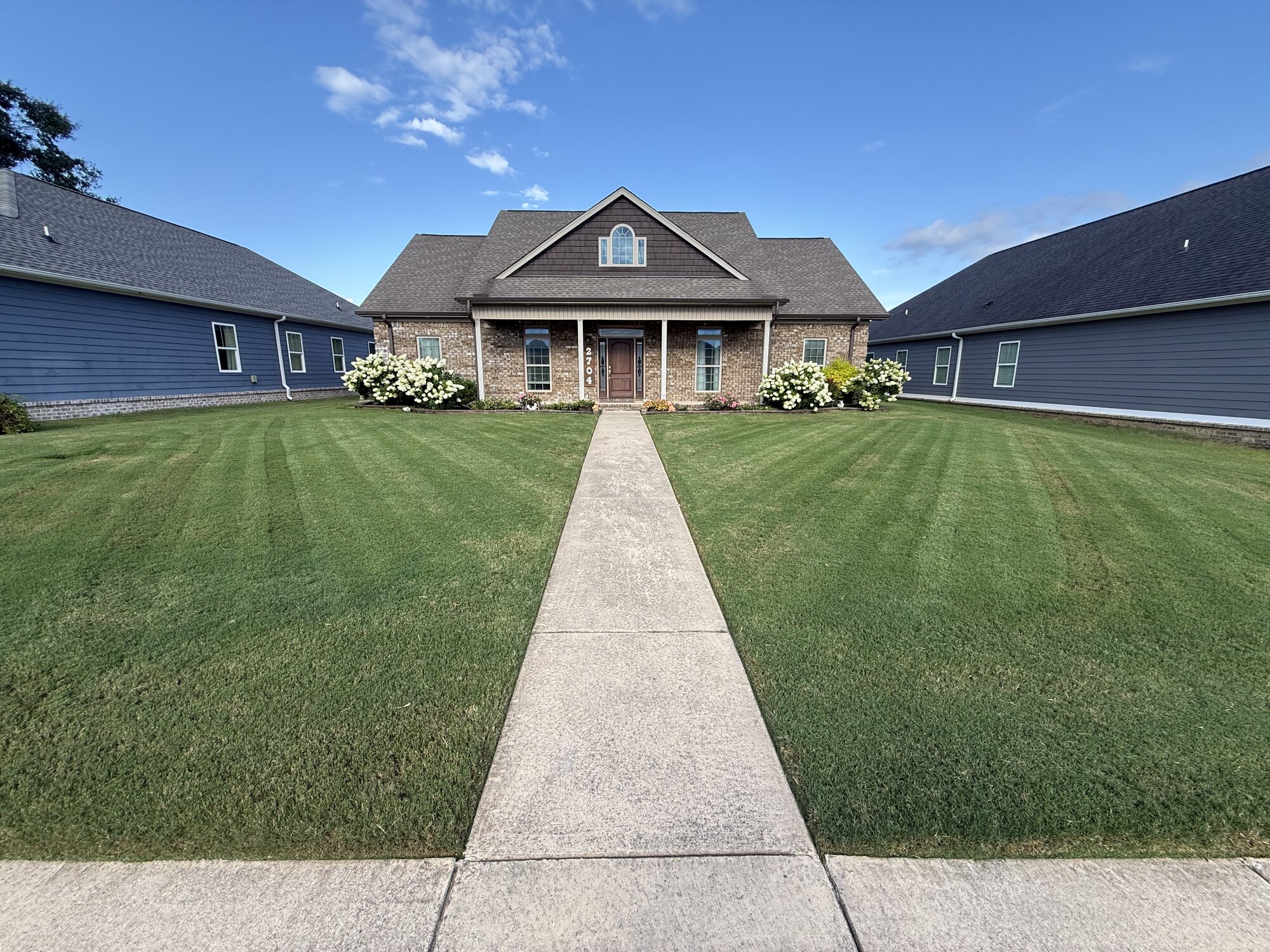 Freshly mowed and striped front lawn of a brick home in Hartselle, AL